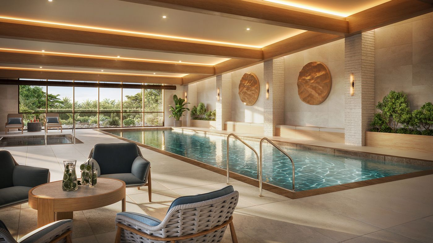 The Stillwater indoor pool, with lounge seating alongside it and full-height windows onto the garden.